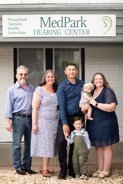 A photo of the Trujillo family standing outside the MedPark Hearing Center signage